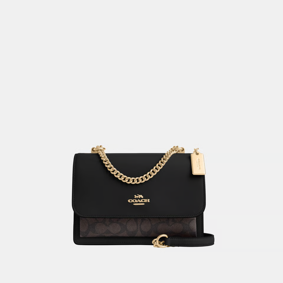 Black handbag with gold chain and Coach logo on a white background
