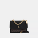 Black handbag with gold chain and Coach logo on a white background