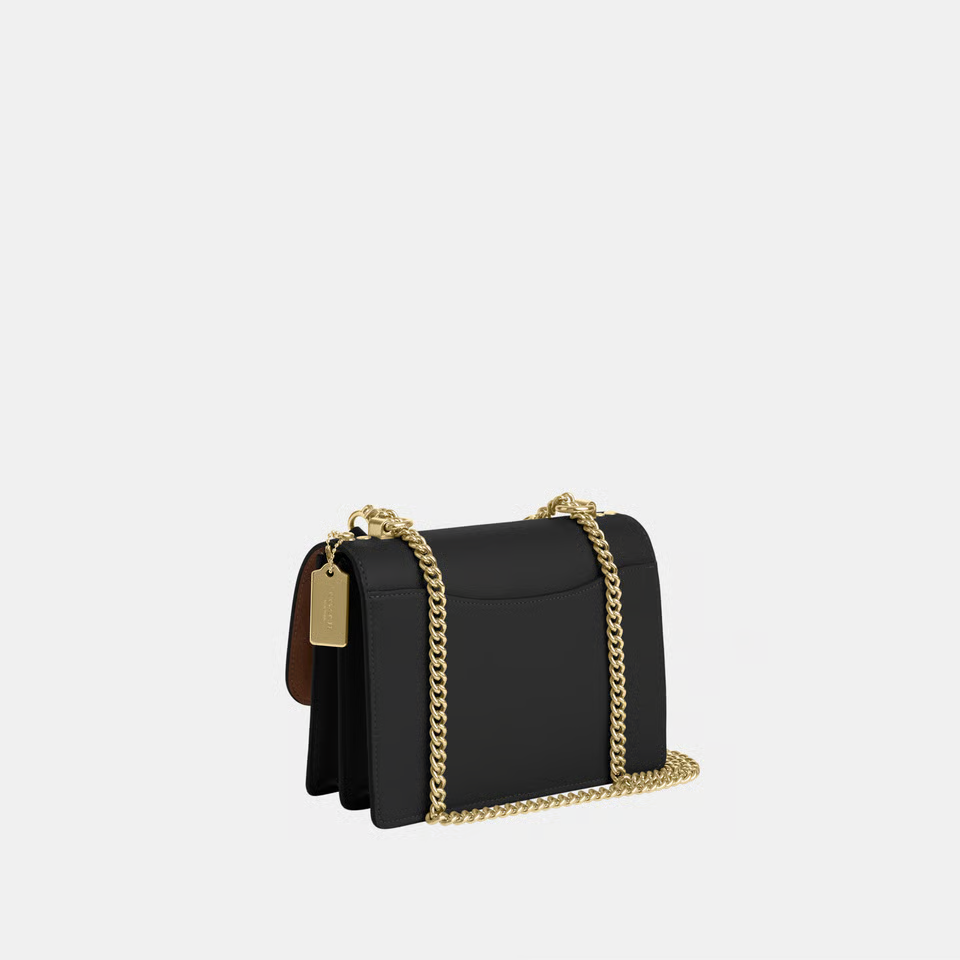 Black handbag with gold chain detail on a white background